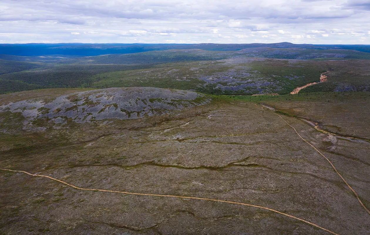 Mönkijäpolut viivoittavat tunturimaisemaa. Maisemasta vaaleana erottuu kuvassa oikealla sijaitseva aktiivinen kaivausalue.