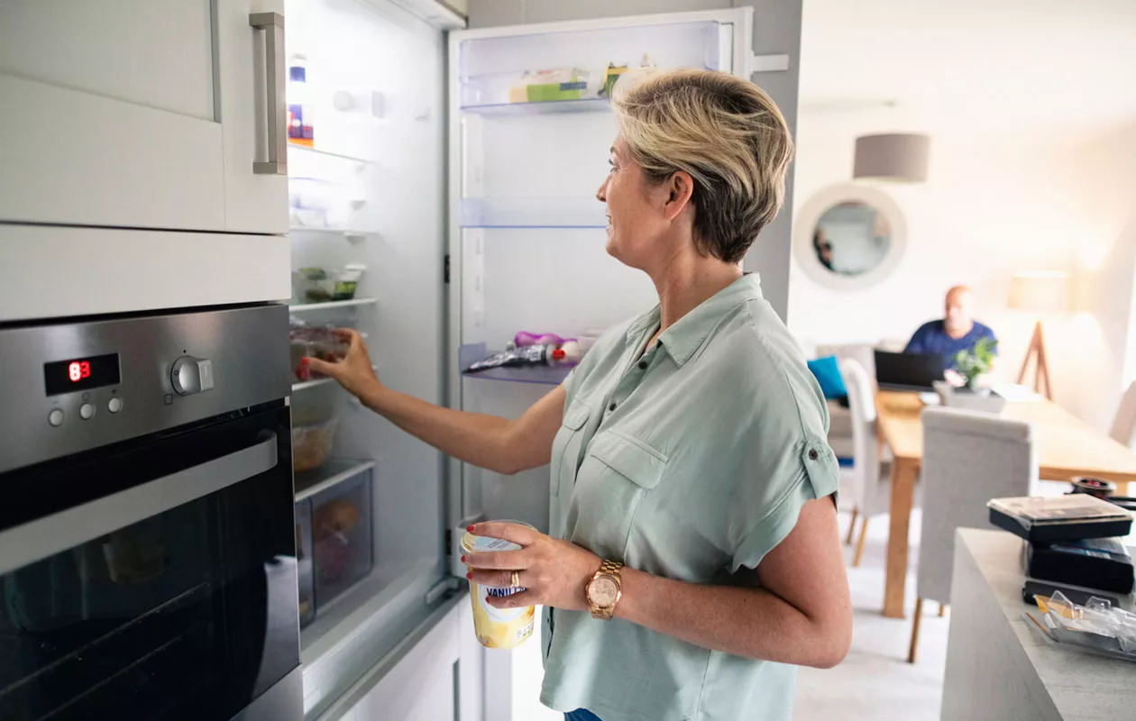 Nainen seisoo jääkaappipakastimen edessä. Tuottee, joissa on parasta ennen -päivämäärä on syytä säilyttää oikein, etenkin, jos ne aikoo pakastaa.