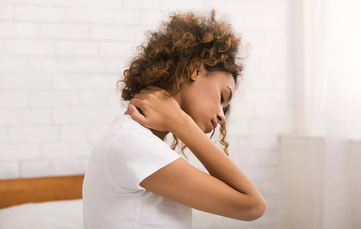 Ahdistunut nainen, joka kärsii niska-hartiakivuista. Miltä ahdistus tuntuu fyysisesti? Psyokologin mukaan usein esimerkiksi niska- ja hartiaoireilta.