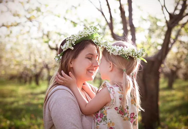 Äiti ja lapsi kuvassa kukkaseppeleet päässä.