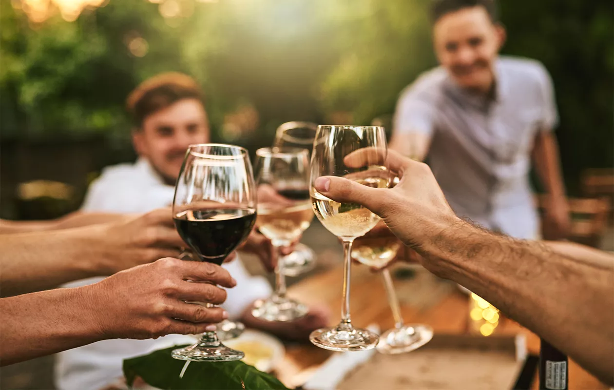Kuva ihmisistä juomassa viiniä. Ihmisillä voi olla hyvinkin erilaiset päihdearvot, myös parisuhteessa.
