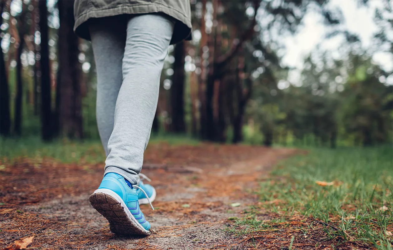 Nainen kävelee metsässä. Nivelrikko voi aiheuttaa ikäviä oireita ja kipuja, mutta nivelrikkoisenkin olisi tärkeää pysyä liikkeessä.