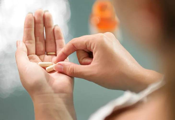 Hapoton maha voi myös nostaa mahasyövän riskiä. Kuvassa nainen, joka pitelee kädessään vitamiinitabletteja. 