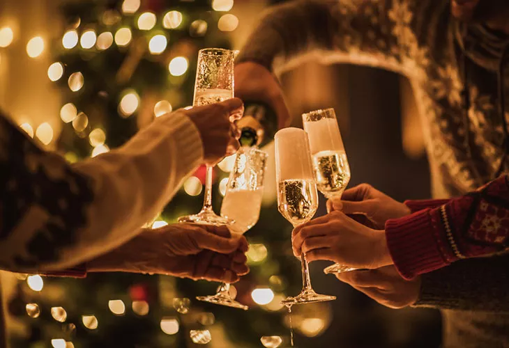 Alkoholinkäyttö kuuluu monen suomalaisen jouluun. Kuvassa joukko ihmisiä pitelee kuohuviinilaseja. 
