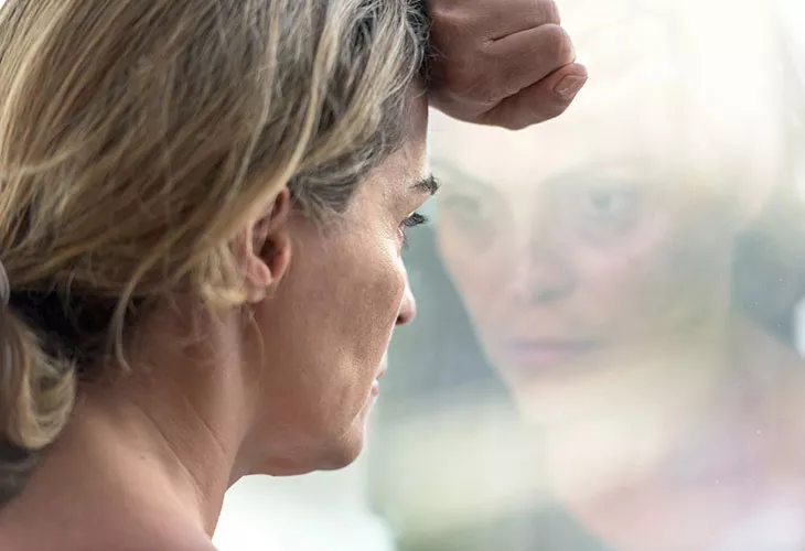 On mahdollista, että e-pillerit aiheuttavat vakaviakin mielialaoireita. Kuvassa nainen katsoo ikkunasta ulos.