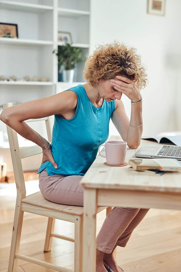 Tyytymättömyys työhön – kuvassa nainen katsoo väsyneenä työpöytäänsä.