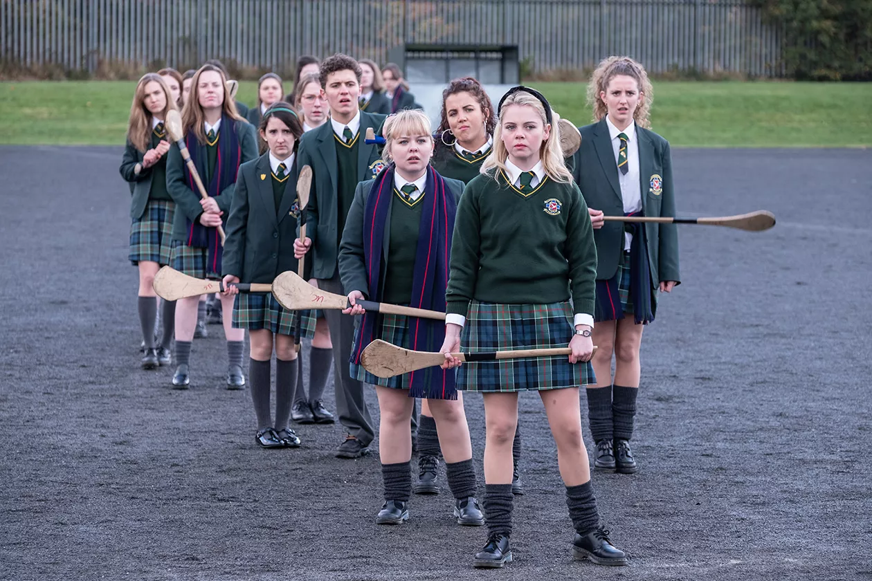 Kuvassa Derry Girls-sarjan hahmot seisovat pelikentällä.