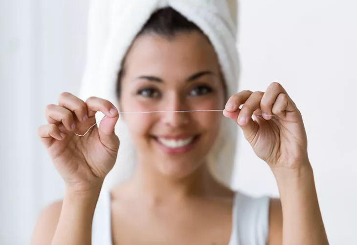 Hammaskivi kertyy ajan saatossa. Sitä voi ehkäistä hyvällä suuhygienilla. Kuvassa nainen hammaslangan kanssa. 