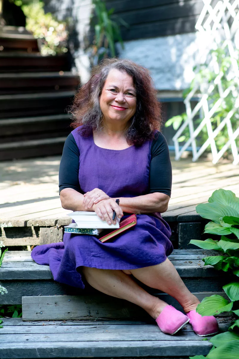 Kirjailija Leena Lehtolainen, 57, istuu portailla päiväkirjat sylissään. 