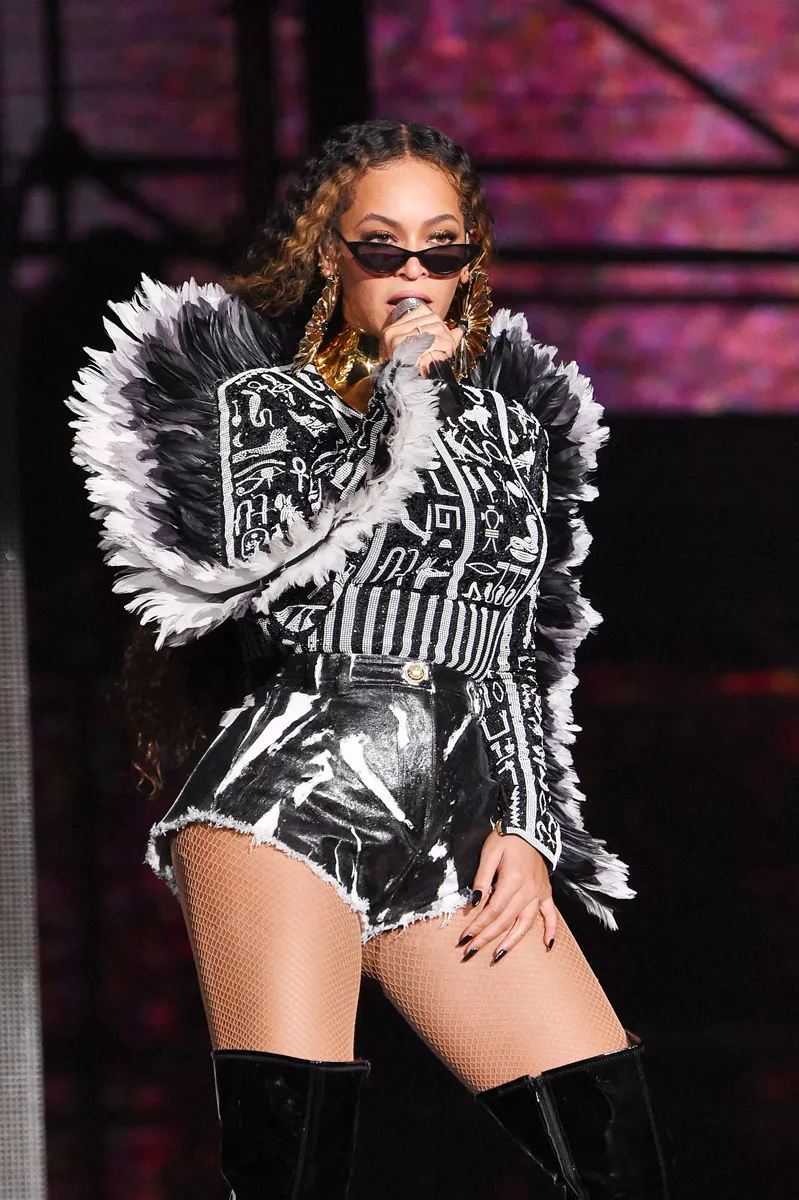 Beyoncé mustavalkoisessa esiintymisasussa, mikrofoni kädessään ja aurinkolasit nenällään niin, että hänen silmänsä näkyvät.