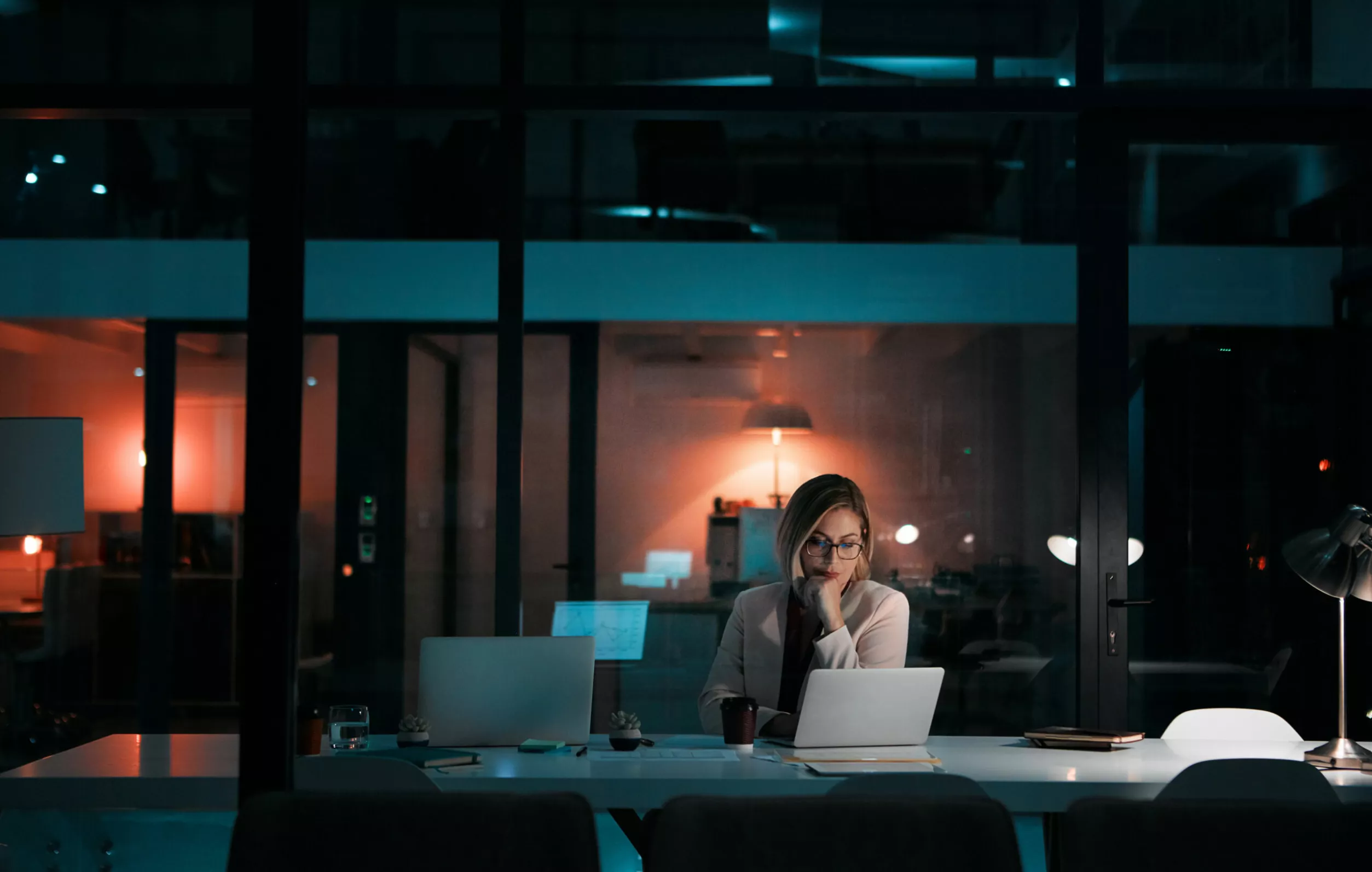 Nainen työskentelee yksin muuten pimeällä toimistolla.