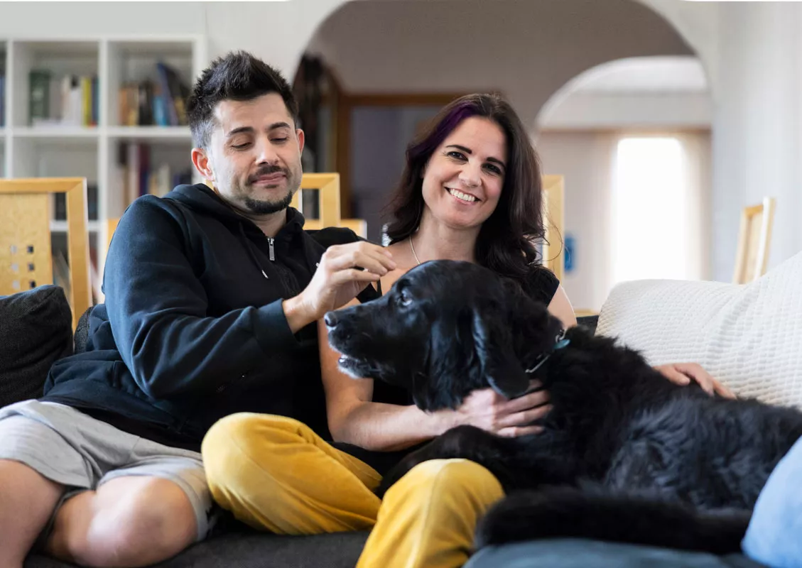 Salima Peippo, hänen miehensä Christian Fernandez ja perheen Max-koira kotisohvallaan. 