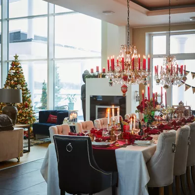 Perhe teetti 5-metrisen pöydän, jotta suku mahtuu juhla-ate­rioille. Näyttävät kattokruunut Hanna-Stiina somistaa jouluun punaisin kynttilöin. Olohuoneeseen tulvii koko seinän ikkunasta.
