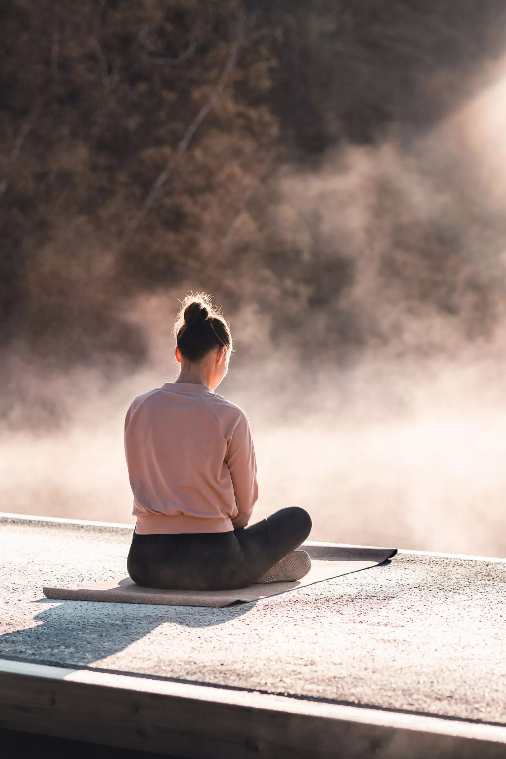 PGAD-kiihottumishäiriö voi helpottaa mindfulnessin avulla. Nainen risti-istunnassa joogamaton päällä usvassa.