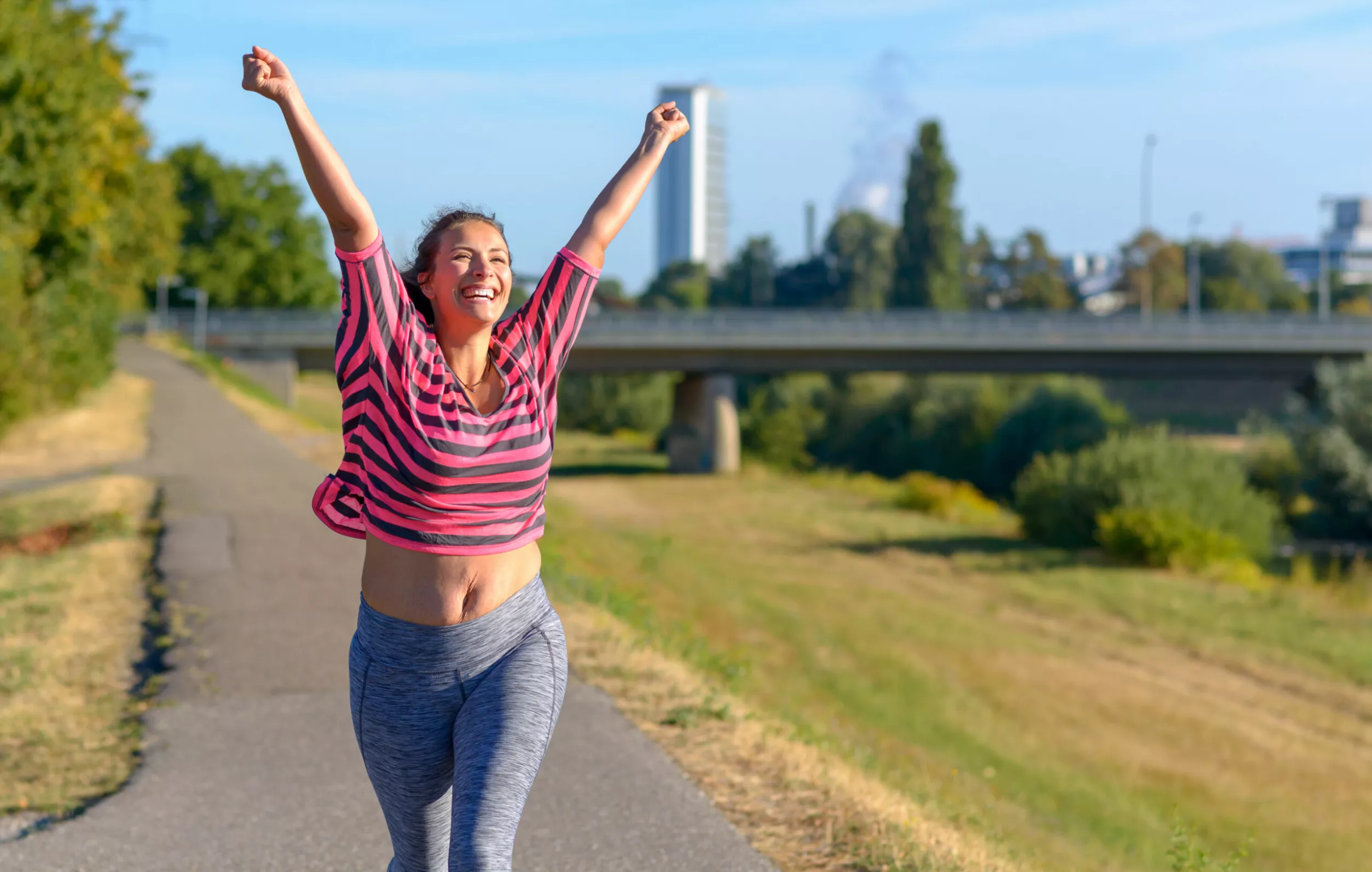 Juoksuohjelma 5 km matkalle – nainen tuulettaa saavutettuaan juoksutavoitteen