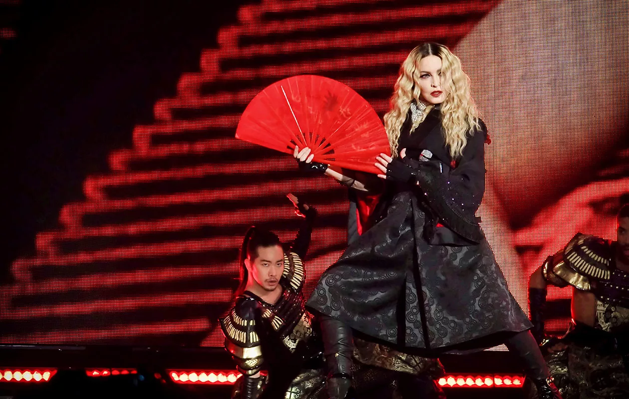 Madonna mustassa asussa punainen viuhka kädessään.